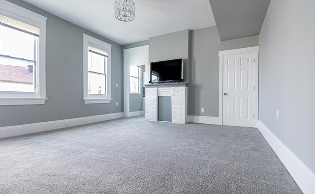 unfurnished living room with carpet flooring, a fireplace, and baseboards