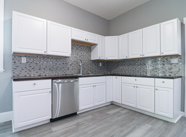 kitchen featuring a sink, dark countertops, light wood finished floors, decorative backsplash, and dishwasher