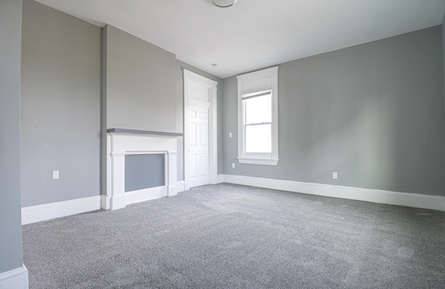 unfurnished living room featuring carpet and baseboards