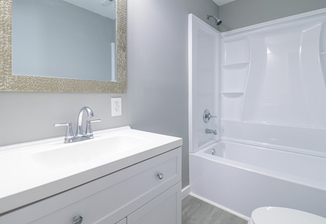 bathroom featuring vanity, toilet, wood finished floors, and  shower combination