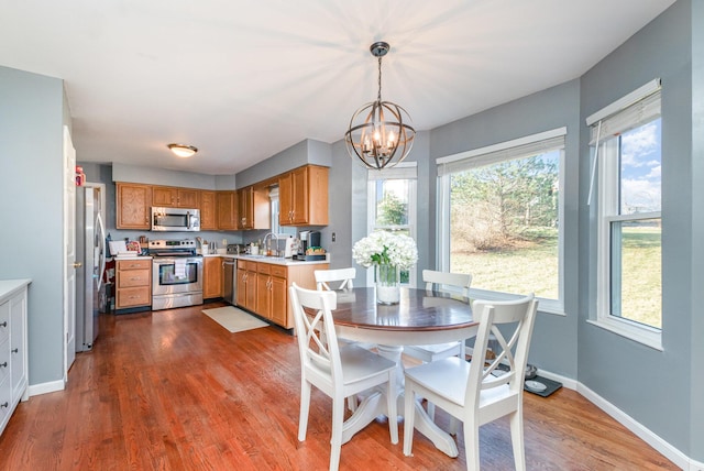 kitchen with dark wood-type flooring, light countertops, an inviting chandelier, stainless steel appliances, and a sink