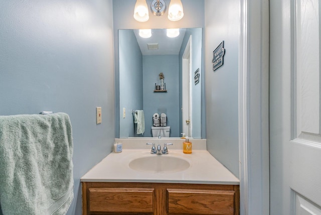 half bathroom featuring toilet, an inviting chandelier, and vanity