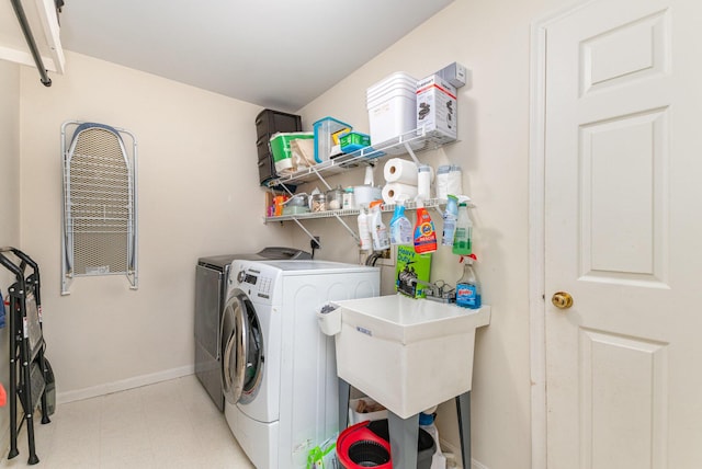 clothes washing area with laundry area, light floors, baseboards, and separate washer and dryer