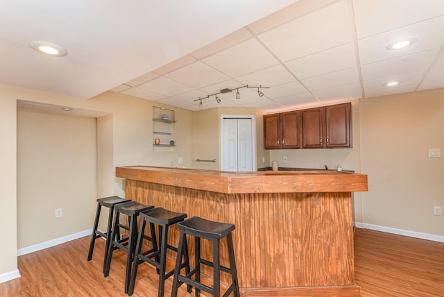 bar featuring wet bar, light wood-style floors, and baseboards