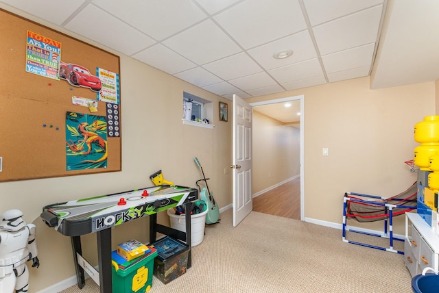 recreation room with carpet flooring, baseboards, and a drop ceiling