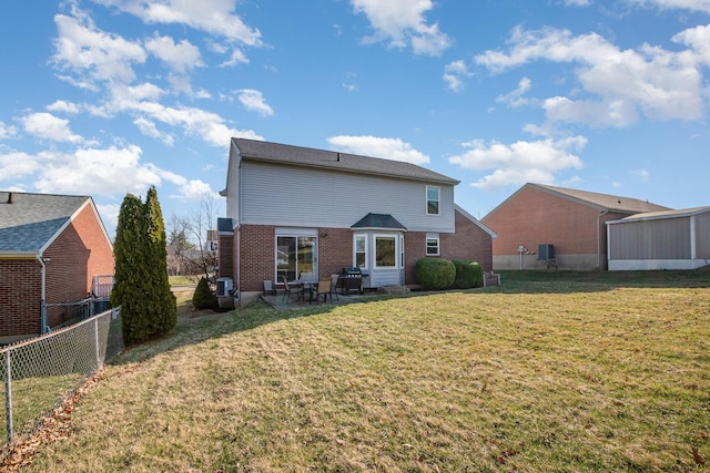 rear view of house with brick siding, a fenced backyard, a patio area, and a yard