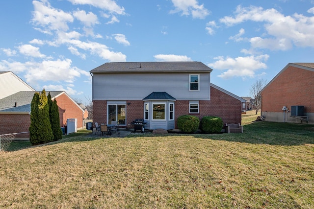 rear view of property with a yard, a patio, brick siding, and fence