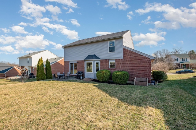 rear view of property with a patio area, a lawn, and brick siding