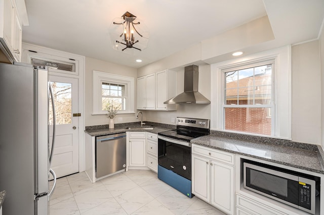 kitchen featuring a sink, white cabinets, appliances with stainless steel finishes, wall chimney range hood, and marble finish floor