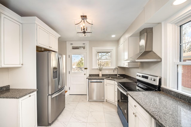 kitchen with appliances with stainless steel finishes, marble finish floor, white cabinetry, wall chimney exhaust hood, and a sink