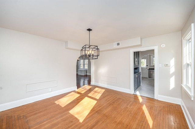 unfurnished room with visible vents, baseboards, an inviting chandelier, and light wood-style flooring