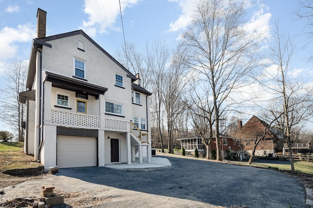 view of property exterior featuring a garage, driveway, and a chimney