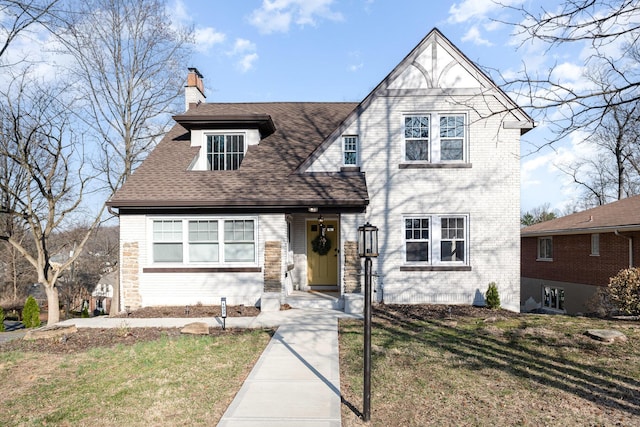 view of front of house with a chimney, a front yard, and a shingled roof