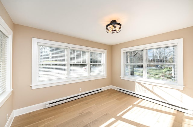 unfurnished room featuring a baseboard heating unit, baseboards, light wood-style floors, and a baseboard radiator