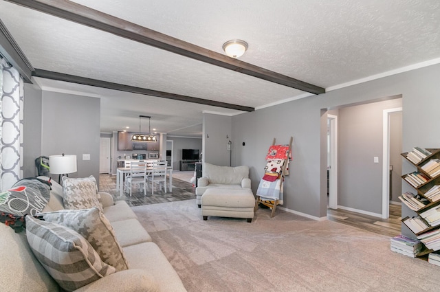 living area featuring beamed ceiling, light carpet, baseboards, and a textured ceiling