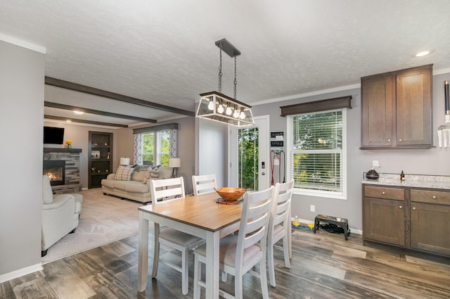 dining room featuring dark wood finished floors, a fireplace, and a textured ceiling