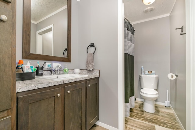 bathroom with wood finished floors, a textured ceiling, ornamental molding, and vanity