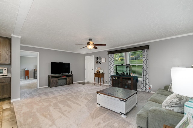 living room with baseboards, ceiling fan, light colored carpet, ornamental molding, and a textured ceiling