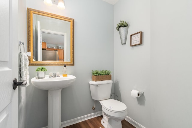 bathroom featuring toilet, wood finished floors, baseboards, and a sink