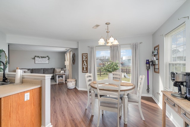 dining space with visible vents, wood finished floors, baseboards, and a chandelier