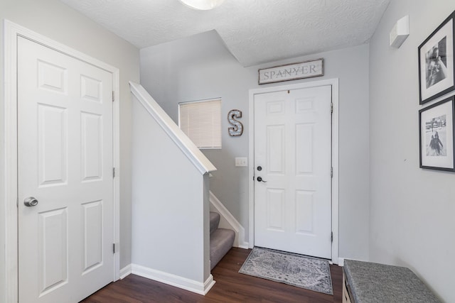 entrance foyer with stairs, baseboards, a textured ceiling, and dark wood-style flooring