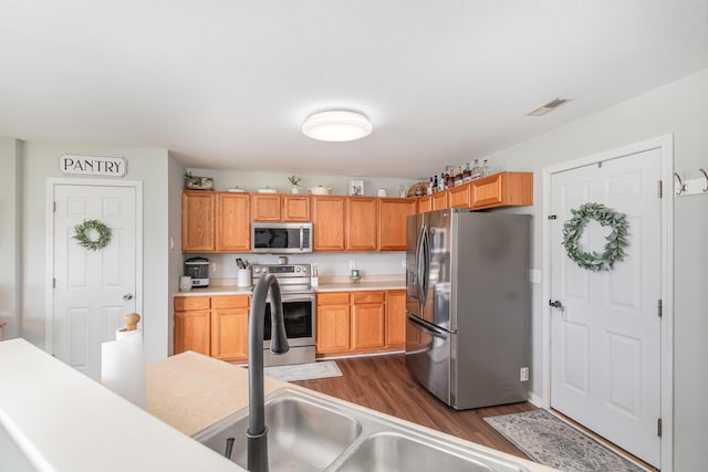 kitchen with stainless steel appliances, visible vents, dark wood-style floors, and light countertops