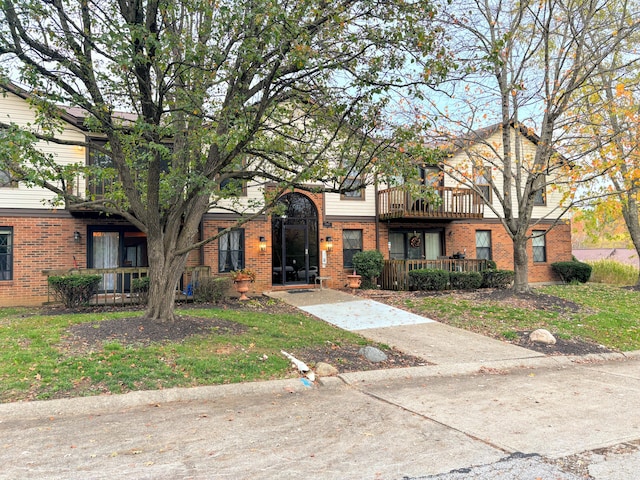 view of front of house featuring brick siding and a balcony