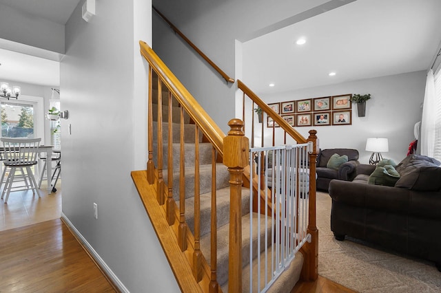 stairs with recessed lighting, an inviting chandelier, baseboards, and wood finished floors