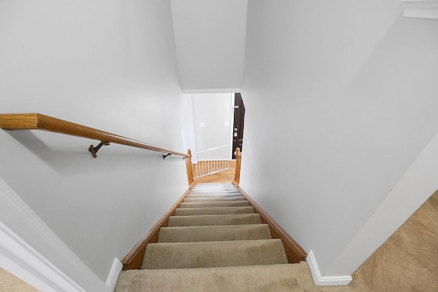 stairway featuring baseboards and carpet floors