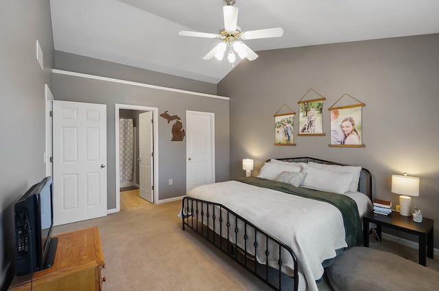 bedroom featuring lofted ceiling, connected bathroom, baseboards, light colored carpet, and ceiling fan