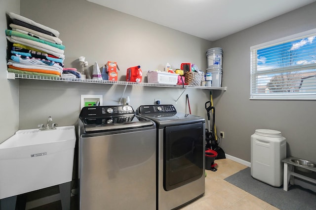 laundry room with washer and clothes dryer, a sink, light tile patterned floors, baseboards, and laundry area