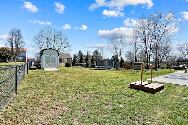 view of yard with an outbuilding, a storage unit, a fenced backyard, and a trampoline