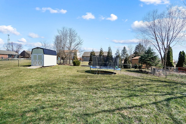 view of yard with an outdoor structure, a trampoline, a fenced backyard, and a shed