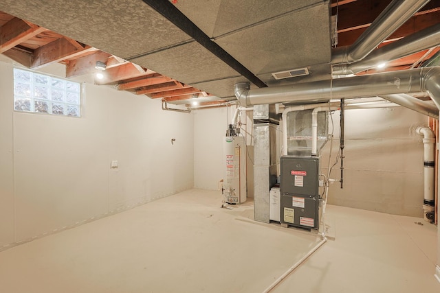 basement with gas water heater, heating unit, and visible vents