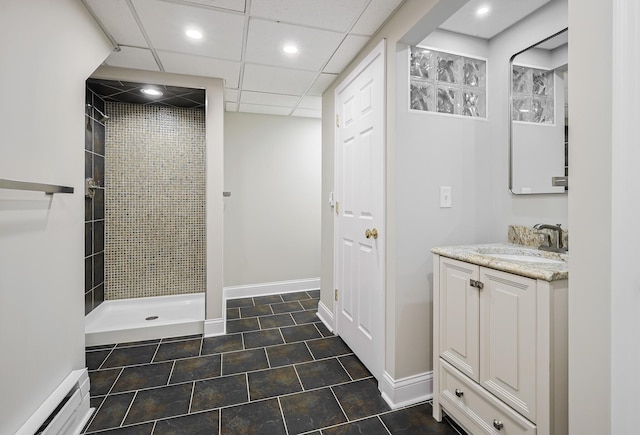 bathroom with a baseboard heating unit, vanity, baseboards, and a tile shower