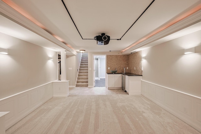 basement with stairway, light carpet, and wainscoting