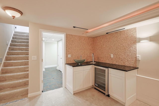 kitchen with dark stone countertops, wine cooler, and white cabinets