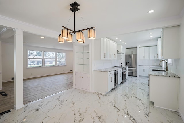 kitchen with a sink, appliances with stainless steel finishes, open floor plan, and white cabinets