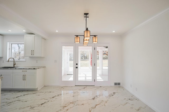 kitchen with a sink, visible vents, baseboards, and marble finish floor