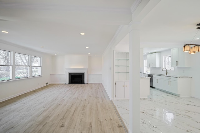 unfurnished living room featuring baseboards, ornamental molding, recessed lighting, a fireplace, and a sink