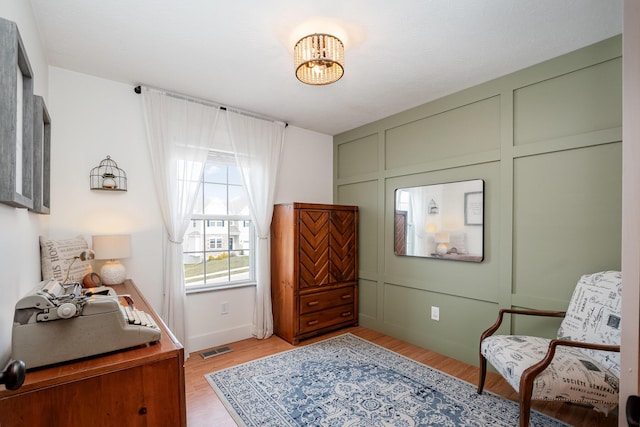 interior space featuring visible vents, light wood finished floors, a chandelier, and a decorative wall