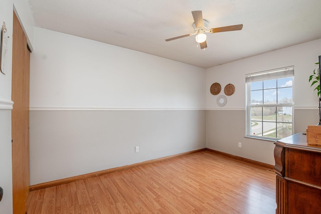 spare room featuring baseboards, wood finished floors, and a ceiling fan