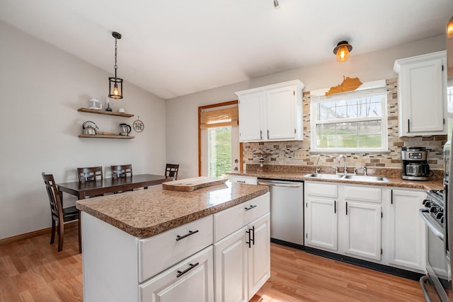 kitchen with a center island, lofted ceiling, appliances with stainless steel finishes, light wood-style floors, and a sink