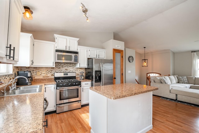 kitchen with a sink, a kitchen island, open floor plan, stainless steel appliances, and lofted ceiling