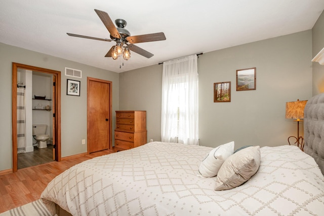 bedroom with visible vents, light wood-style flooring, a ceiling fan, ensuite bathroom, and baseboards