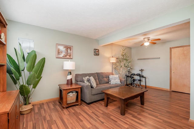 living area with ceiling fan, a textured ceiling, light wood-type flooring, and baseboards