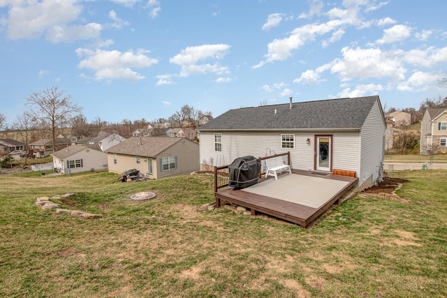 rear view of property with a deck, a yard, a residential view, and roof with shingles