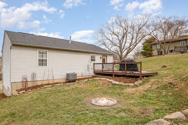 rear view of house featuring cooling unit, a wooden deck, and a yard