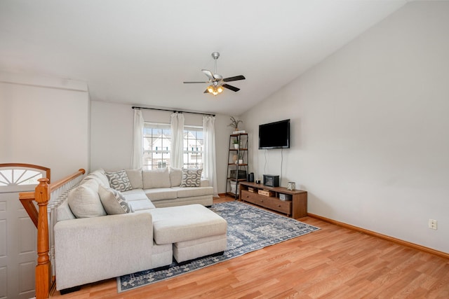 living room featuring light wood-type flooring, lofted ceiling, baseboards, and a ceiling fan