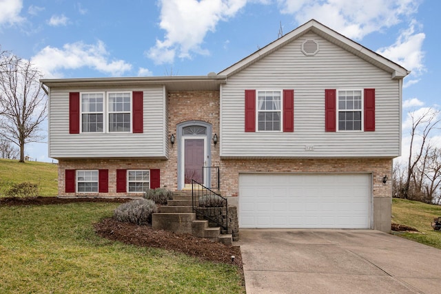 bi-level home with a garage, a front yard, brick siding, and driveway